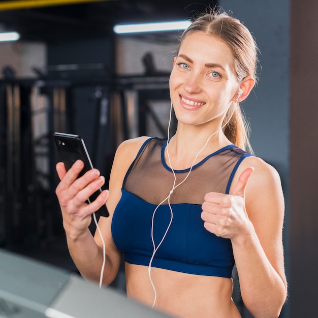 Free photo woman using smartphone in gym