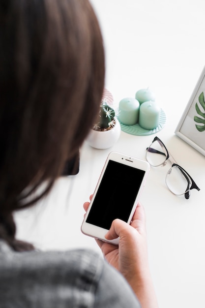 Woman using smartphone at table with eyeglasses and candles