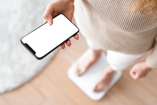 Free Photo woman using smartphone on weighing scale innovative technology