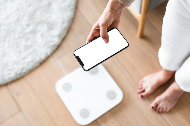 Free photo woman using smartphone next to weighing scale  innovative technology