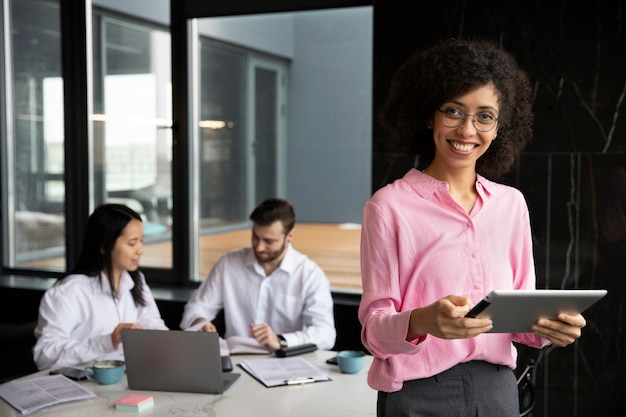 Woman using a tablet to work while her colleagues are using a laptop