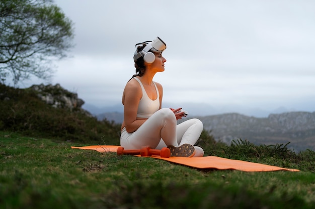 Free photo woman using vr glasses to exercise outdoors in nature