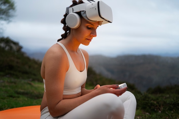 Free photo woman using vr glasses to exercise outdoors in nature