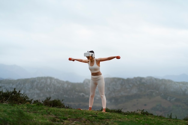 Free Photo woman using vr glasses to exercise outdoors with weights