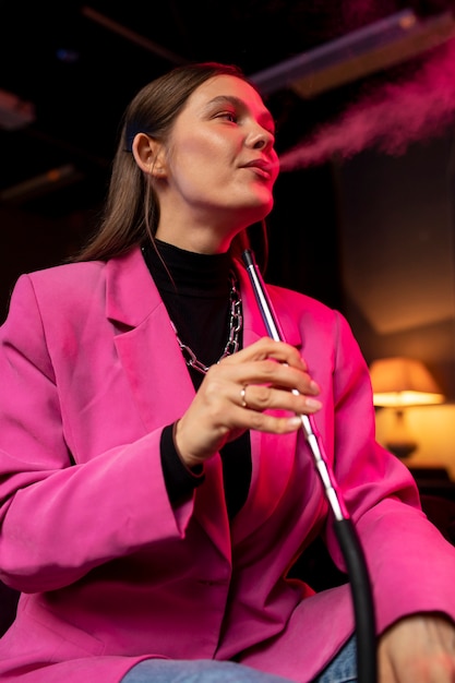 Free photo woman vaping from a hookah indoors