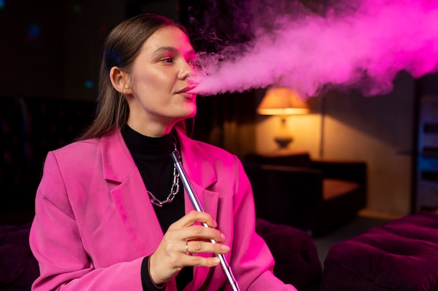 Free photo woman vaping from a hookah indoors