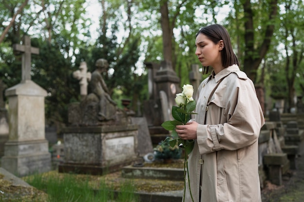 Woman visiting a grave at the cemetery and bringing flowers