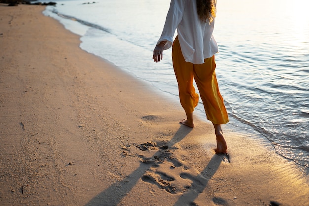 Free photo woman walking on the beach back view