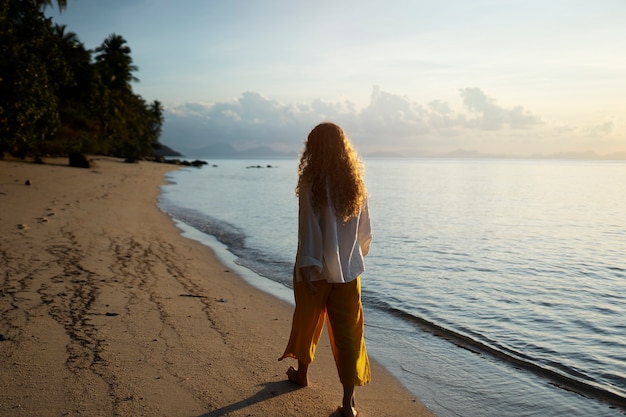 Free photo woman walking on beach full shot