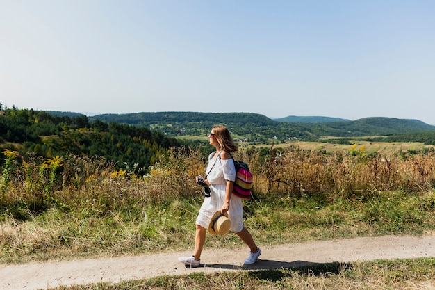 Woman walking sideways with landscape as background