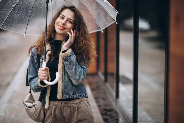 Free Photo woman walking under the umbrella in a rainy weather