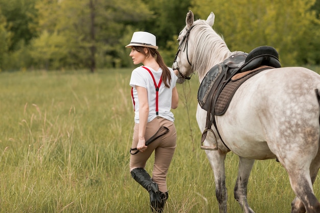 Free photo woman walking with a horse in the countryside