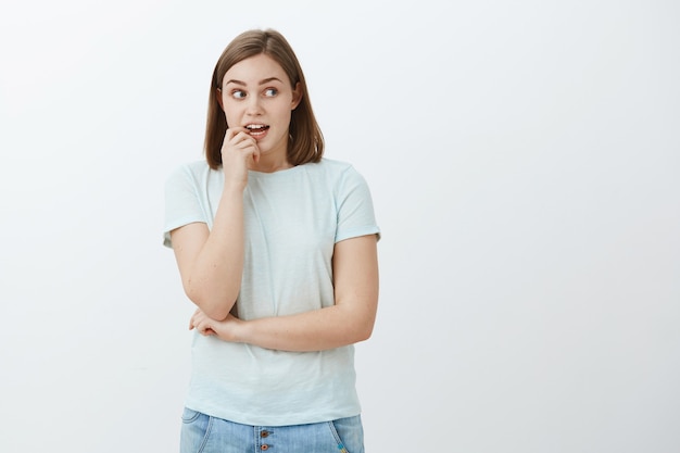 Woman wants grab sweets hesitating if diet allows. Intrigued and curious excited and focused cute woman biting fingernail while thinking gazing with desire