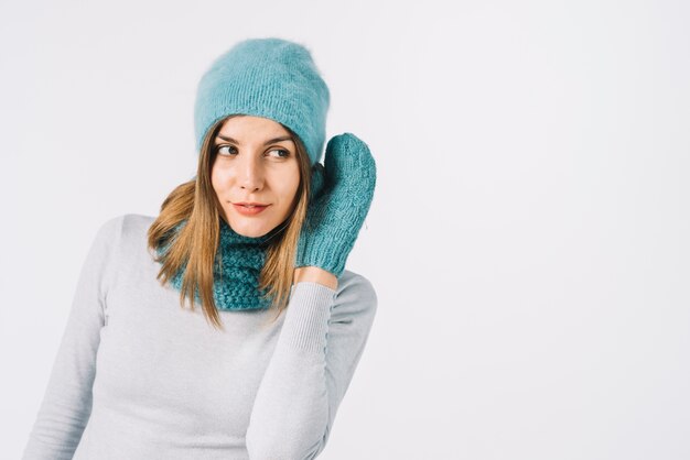 Woman in warm accessories holding hand near ear