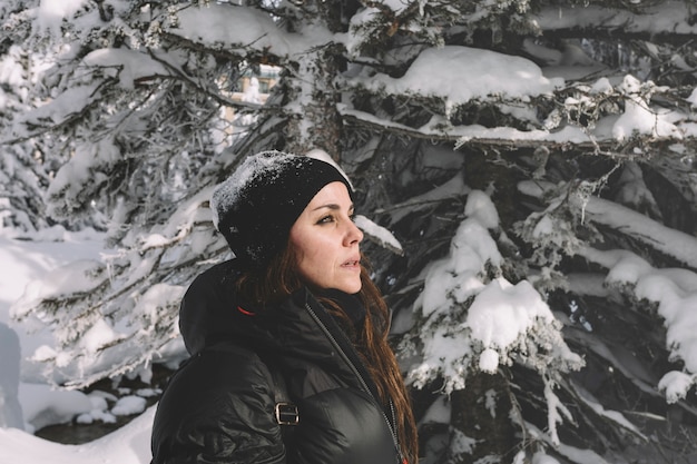 Woman in warm clothes on pine trees background