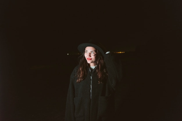 Woman in warm clothes standing in dark street 