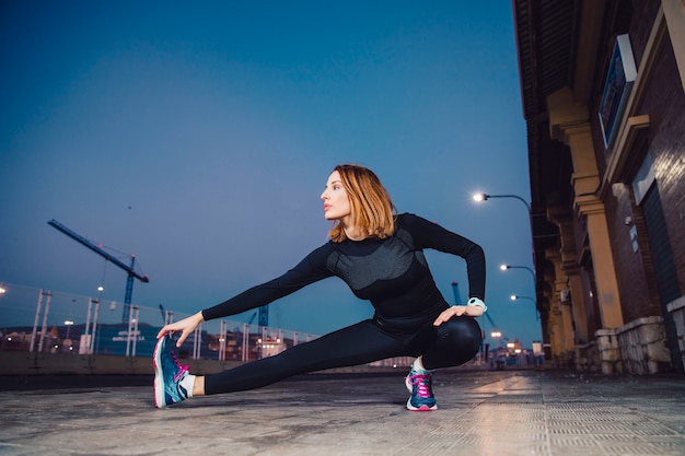 Free photo woman warming up legs on pavement