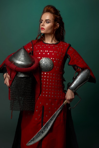 Free Photo woman warrior posing with dagger, helmet in hand.