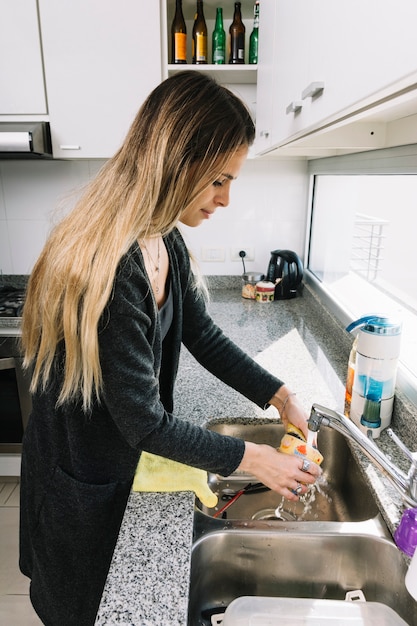 Free photo woman washing container in kitchen sink