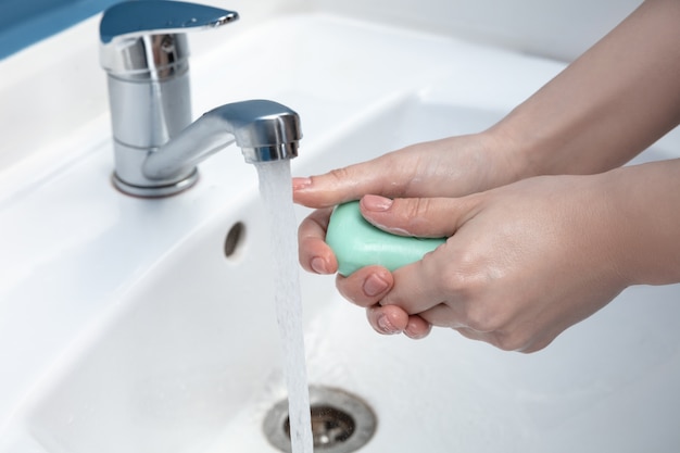 Woman washing hands carefully in bathroom close up. Prevention of infection and flu virus spreading