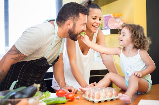 Woman watching daughter feeding bell pepper to her father