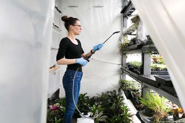 Woman watering plants in hothouse