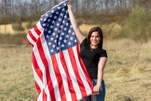 Woman waving flag of USA outside during Independence Day