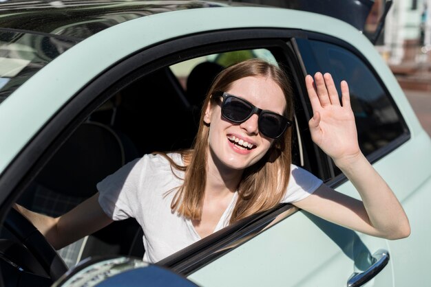 Woman waving from car before voyage