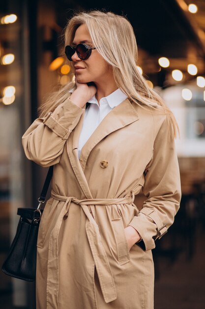 Woman wearing beige coat and walking in the street on Christmas