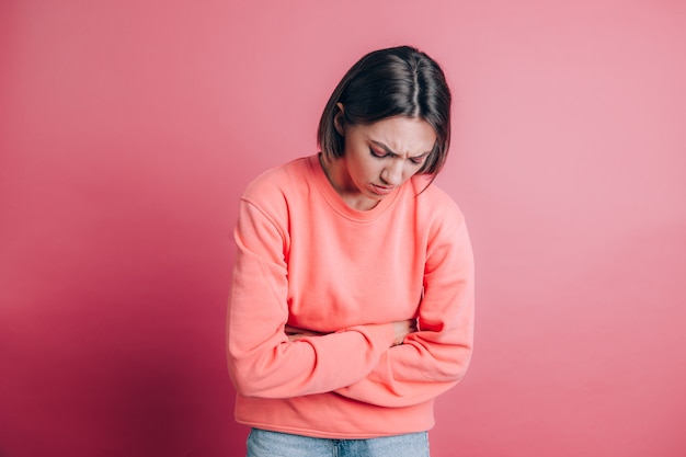 Free photo woman wearing casual sweater on background suffering stomach ache with painful grimace, feeling sudden period cramps, gynecology concept