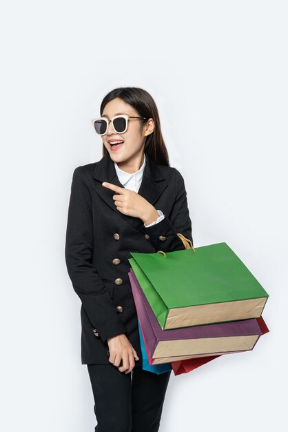 The woman wearing dark clothes and glasses, along with many bags, to go shopping