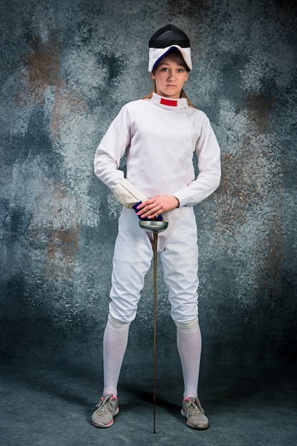 Free photo the woman wearing fencing suit with sword against gray