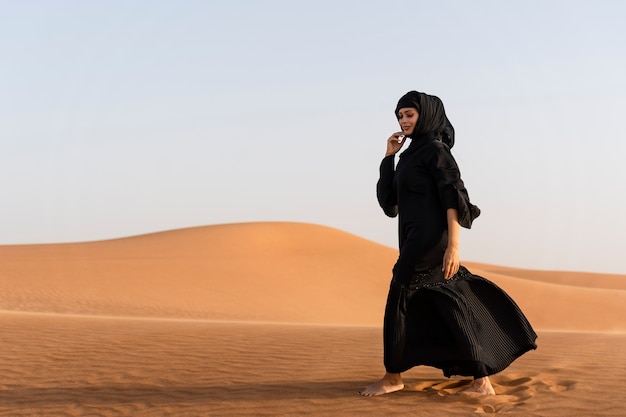 Free photo woman wearing hijab in the desert