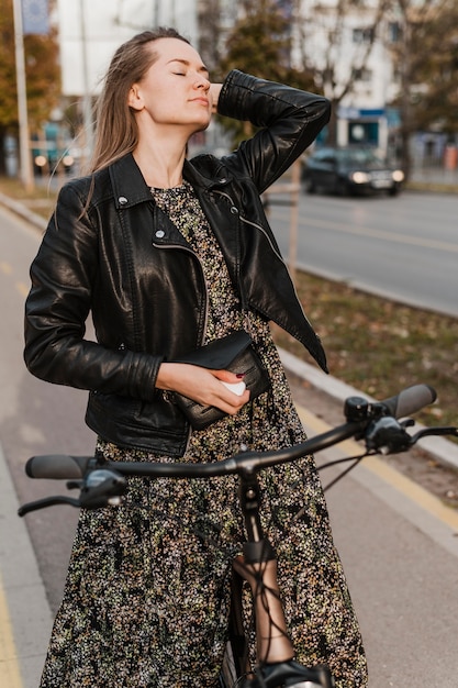 Free photo woman wearing a long dress holding her bike front view