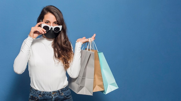 Free photo woman wearing mask and holding shopping bags