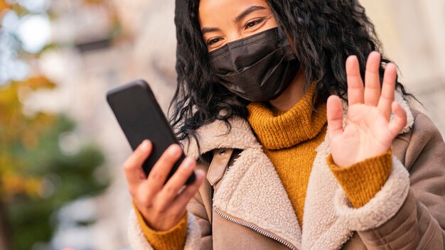 Woman wearing a medical mask while having a video call on her smartphone