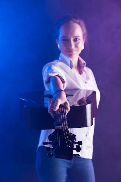 Woman wearing office shirt showing an acoustic guitar