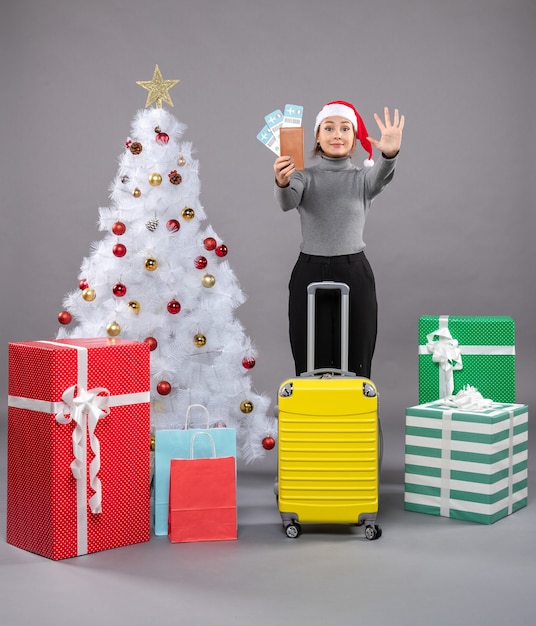 Free Photo woman wearing santa claus hat with luggage next to christmas tree