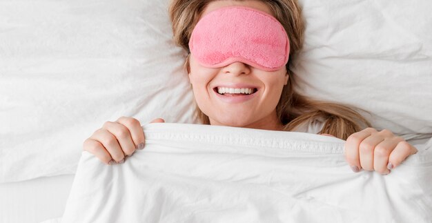 Woman wearing a sleep mask on her eyes and smiles