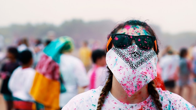 Free photo woman wearing sunglasses and covering her face with a bandana during a painting fiesta