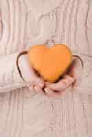 Free photo woman wearing sweater holding orange heart