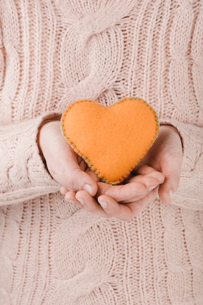 Free Photo woman wearing sweater holding orange heart