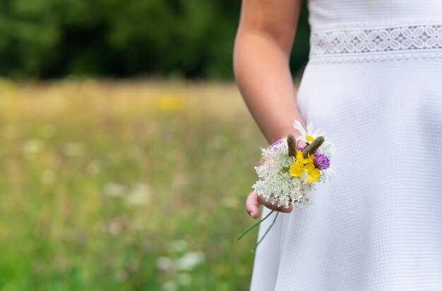 Woman wearing a white dress and holding beautiful colorful flowers