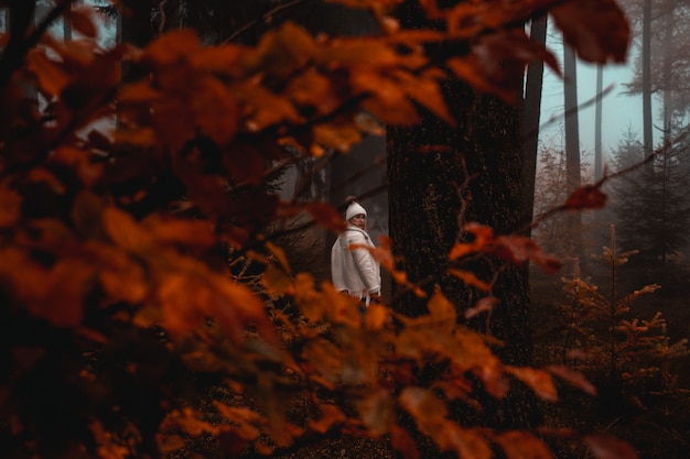 Free photo woman wearing white jacket standing near tree in forest