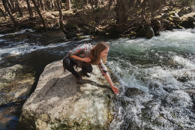 Woman wetting her hand in the river