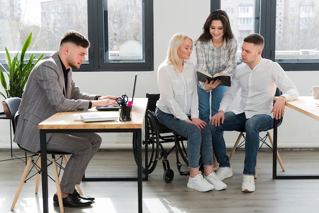 Woman in wheelchair conversing with coworkers at office