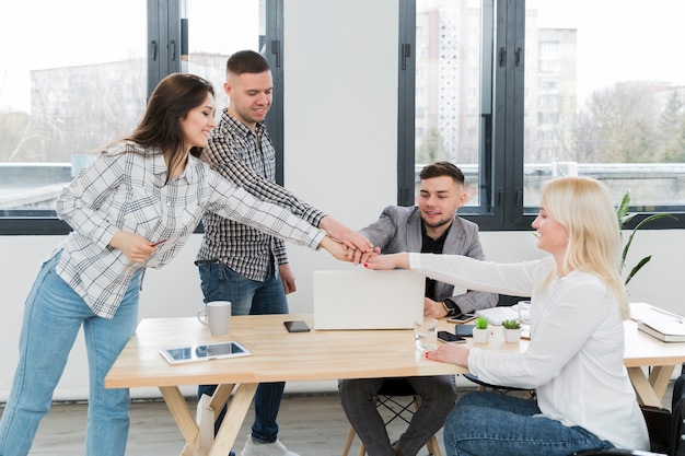 Free photo woman in wheelchair putting her hand together with colleagues