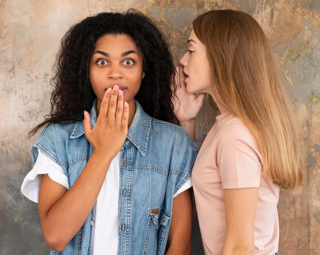 Free Photo woman whispering her friend a secret