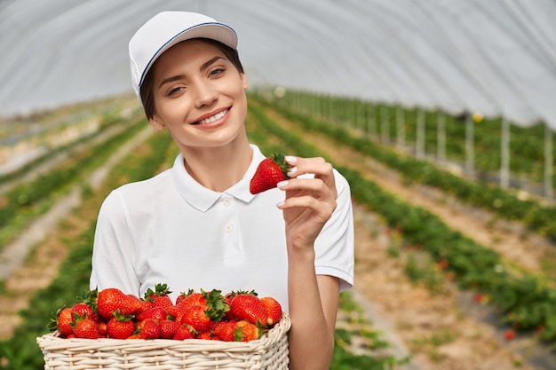 Free photo woman in white cap holding basket with ripe strawberries