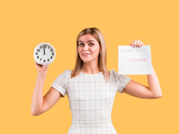 Woman in white dress shows clock and calendar